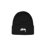 A black knit beanie hat with a white embroidered Stüssy logo on the front cuff, photographed against a clean white background.