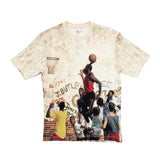 A short-sleeve crewneck t-shirt featuring a distressed, vintage-style cream and tan background with a large graphic print of a basketball game scene. The graphic depicts a player in a red jersey dunking a basketball, with other players and graffiti text in the background.